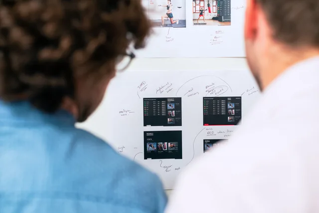 Two business professionals brainstorming and planning software development with a whiteboard in an office. Bedarf an Software und Dienstleistungen im Unternehmen erheben