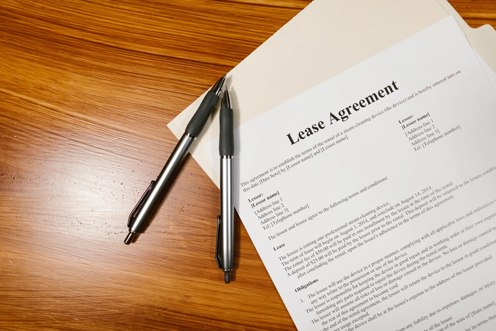 High-angle view of a lease agreement and pens on a wooden desk.